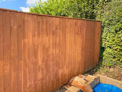 Wooden Fence Panels Being Painted With Wood Rpeserver. The Lighter Patches Are Where New Paint Is Drying. No People. Copy Space.