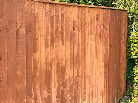 Wooden Fence Panels Being Painted With Wood Rpeserver. The Lighter Patches Are Where New Paint Is Drying. No People. Copy Space.