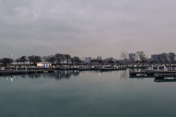 Obraz premium Well lit boat house behind empty docks on calm water with overcast sky in Chicago