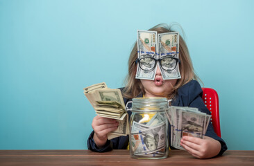 Education for kids how to be rich. Child with dollar bills shoved over glasses covering eyes. Financial independence and ability to earn a lot of money. Back to school