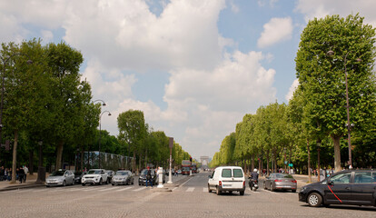 Tourists are walking along the Champs Elysees, vehicles are moving