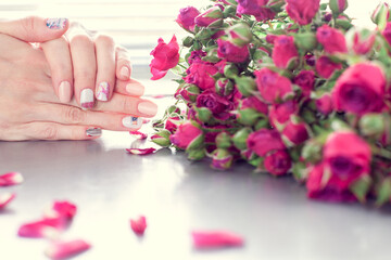 Obraz na płótnie Canvas Female hands with art nail manicure and small pink roses