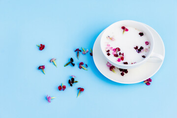 White Cup with vegan milk and flowers on a blue background. Concept of vegetarian drinks and food, herbal teas, beauty and health, Spa