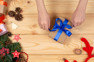 Hands packing Christmas gift on the themed background, top view