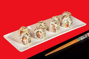 Sushi Sets Nigiri, Uramaki, California, Philadelphia, on a white plate. On a red colored background.