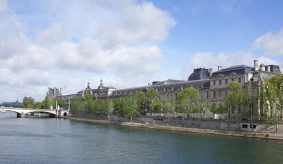 Fototapeta na wymiar View of the Louvre from the bridge of Arts. On the promenade of Francois Mitterrand walk people