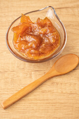 Glass pot with a delicious homemade apple and onion chutney, with cinnamon on a light wooden board. Perfect jam for breakfast. Breakfast, cooking, food concept.