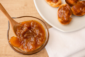 Glass pot with a delicious homemade apple and onion chutney, with cinnamon on a light wooden board. Perfect jam for breakfast. Breakfast, cooking, food concept.