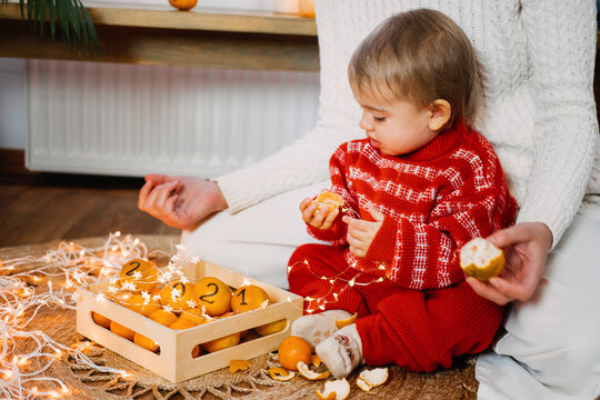 Christmas Celebration At Home In New Normal 2021. Family Celebrating Christmas In Time Of COVID Pandemic. Baby Toddler Girl With Mom Having Fun With Oranges, Tangerines With Numbers 2021.