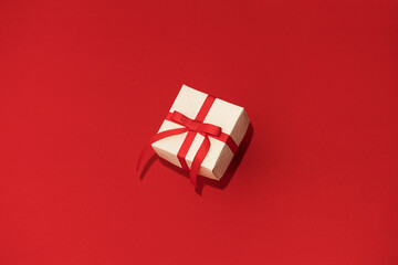 Fototapeta na wymiar White gift box with red ribbon on red background. Concept of Valentins Day, copy space and mock up