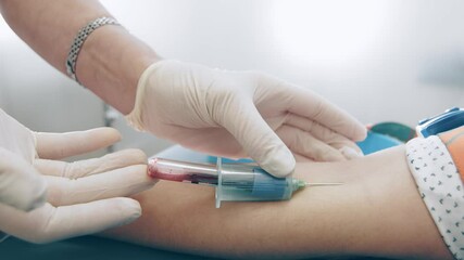 A lab worker mixes a blood sample. The laboratory assistant holds a test tube with freshly collected blood and mixes it. - Powered by Adobe