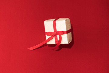 White gift box with red ribbon on red background. Concept of Valentins Day, copy space and mock up