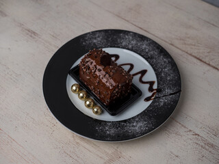 cake with chocolate cream on a plate decorated, view from above, wooden light background, warm atmosphere. place for text
