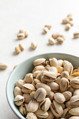 Pistachios. Pistachio nuts in a ceramic round plate, several pistachios are sprinkled on the background