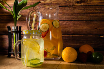 Large glass pitcher with citrus flavored water and homemade lemonade. Glass or jar with drink, lid and straw. Freshness, health and non-alcoholic drinks concept.