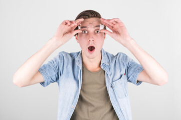 Portrait of a shocked man in eyeglasses looking at camera while raised up glasses. Isolated over white background