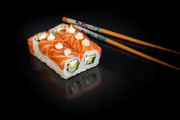 Sushi Sets Uramaki, California, Philadelphia, on a white plate. Festive, New Year concept. Against a dark reflective background.