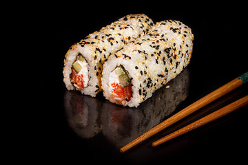 Sushi Sets Uramaki, California, Philadelphia, on a white plate. Festive, New Year concept. Against a dark reflective background.