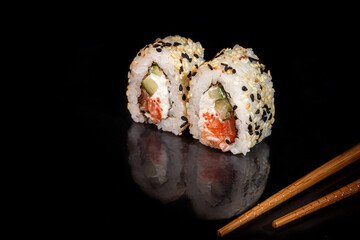 Sushi Sets Uramaki, California, Philadelphia, on a white plate. Festive, New Year concept. Against a dark reflective background.