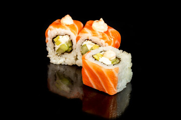 Sushi Sets Uramaki, California, Philadelphia, on a white plate. Festive, New Year concept. Against a dark reflective background.