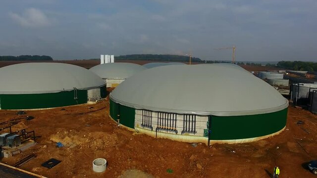 Building of bio gaz station in green field. Gray roofs and green walls of round metal construction.