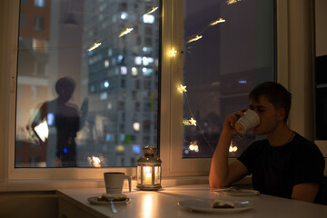 Female with mobile phone silhouette on the window, decorated for christmas and man having his dinner alone