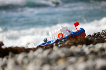 colorful toy plastic boat on the pebble beach close up