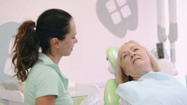 Dentist Appointment. Senior woman smiling listening to her dentist during consultation.
