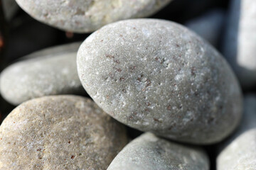 Fototapeta na wymiar smooth and beautiful pebbles on the beach in the sunlight close up