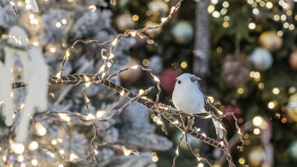 Christmas toy in the form of bird. Decorated christmas tree background. Happy new year concept. Blurred background with lights.