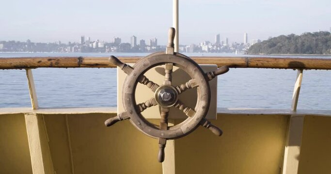 Wooden Ship's Wheel On  Boat Cruising At Sydney Harbour With Sydney Cityscape In Background During Summer In NSW, Australia. - wide shot