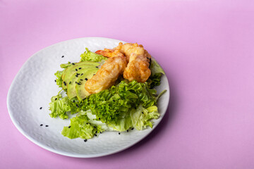 Avocado and king prawns salad on green leaves. Festive dinner. Healthy eating. On a pink background.