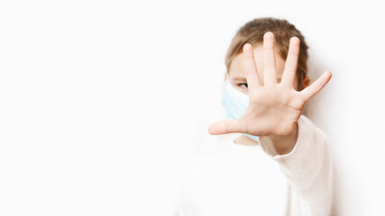 Little girl in a medical mask of protection pm2.5 shows a stop gesture with her palm. Coronavirus. quarantine. Stay at home. keep social distance. Baby on a white background with copy space. epidemic