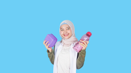 asian muslim woman holding a lunch box and mineral water bottle
