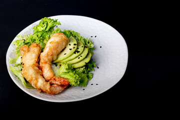Avocado and king prawns salad on green leaves. Festive dinner New Years concept. Healthy eating. On a black reflective background.