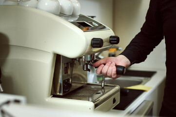 Partial view of barista grinding coffee and making espresso on professional coffee machine