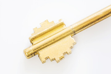 Macro photography of golden key isolated on white background. Selective focus, shallow depth of field.
