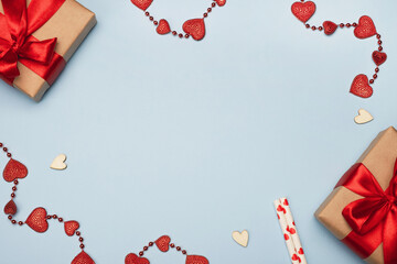 Valentines day composition. Gift boxes, red hearts and festive decor on light blue background. Top view, flat lay, copy space, frame