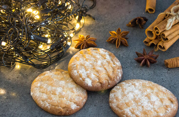 Christmas biscuits with festive decoration. Top view photo of homemade cookies, Christmas lights, tangerines, star anise and cinnamon sticks. 
