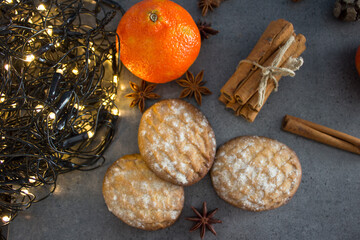 Christmas biscuits with festive decoration. Top view photo of homemade cookies, Christmas lights, tangerines, star anise and cinnamon sticks. 
