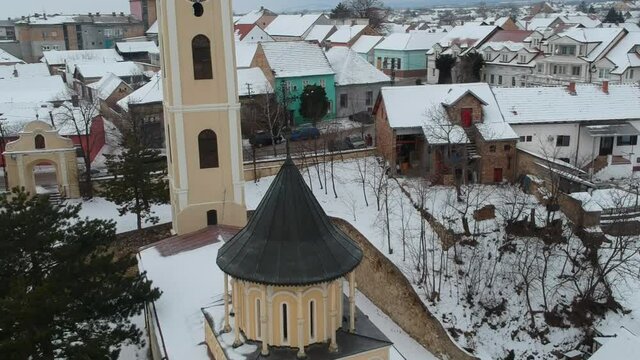 Aerial drone shot of a rural little town in the winter. Snow on the roofs. Clock of a small church.