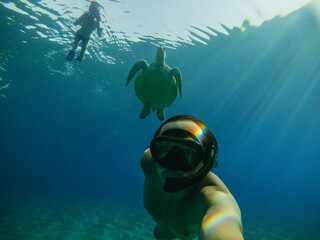 Sea. A man in an underwater mask and fins swims in the sea next to a large turtle. Egypt.
