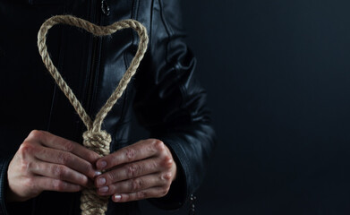 Fototapeta na wymiar Rope in the form of a heart in the hands of a girl on a black background, the concept of relationships