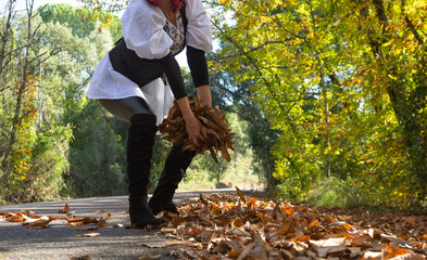 Fototapeta na wymiar Recogiendo hojas amarillas en el borde de carretera entre el bosque de castaños, mujer de pelo rojo 