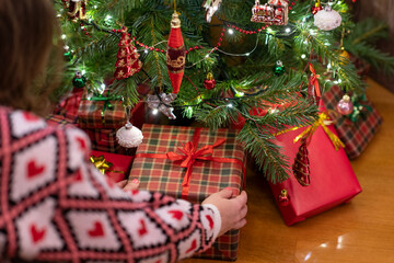 Woman putting gift box under christmas tree. Presents for family.