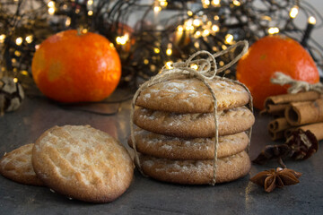 Christmas biscuits with festive decoration. Top view photo of homemade cookies, Christmas lights, tangerines, star anise and cinnamon sticks. 
