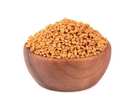 Fenugreek seeds in wooden bowl, isolated on white background. Shambala, helba seeds.