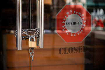 Closed Store due to Coronavirus pandemic. Locked Store Door with Padlock and Chains and Covid 19...