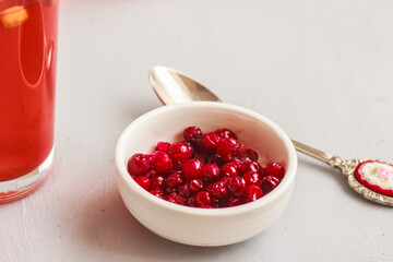 A bowl of frozen lingonberries, berry drink on light background
