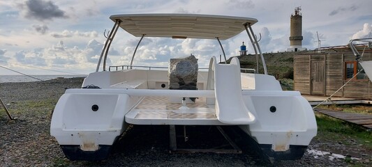 new, white plastic catamaran on the beach in the marina.